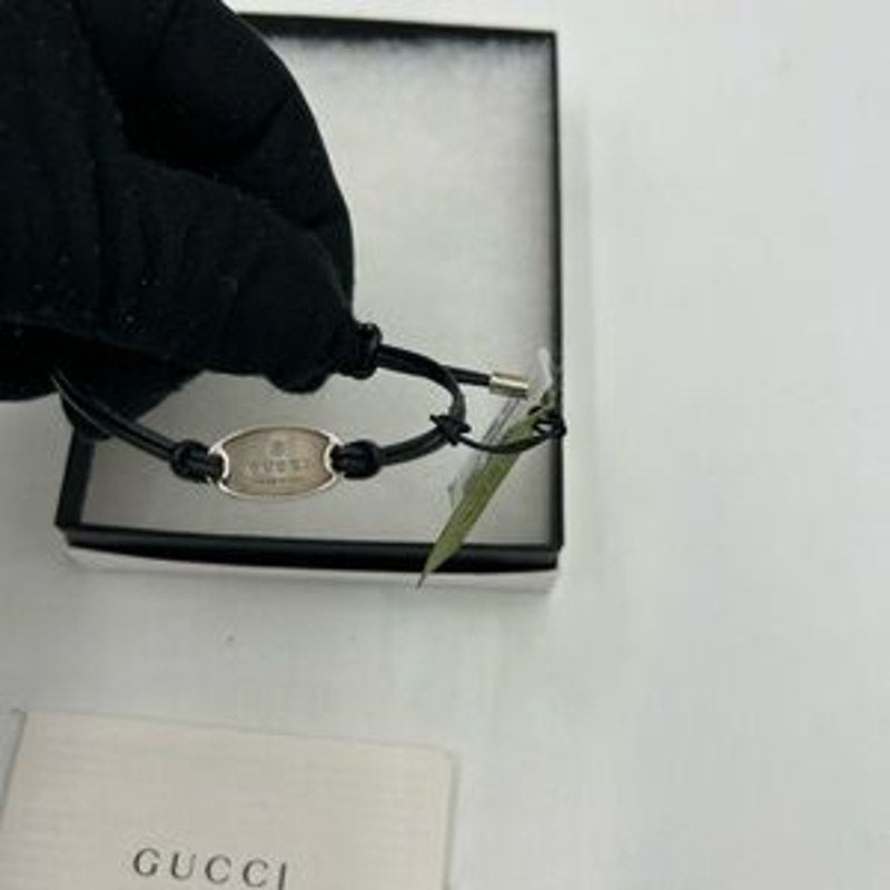 Gucci, black leather cord bracelet with sterling silver logo engraved plaque