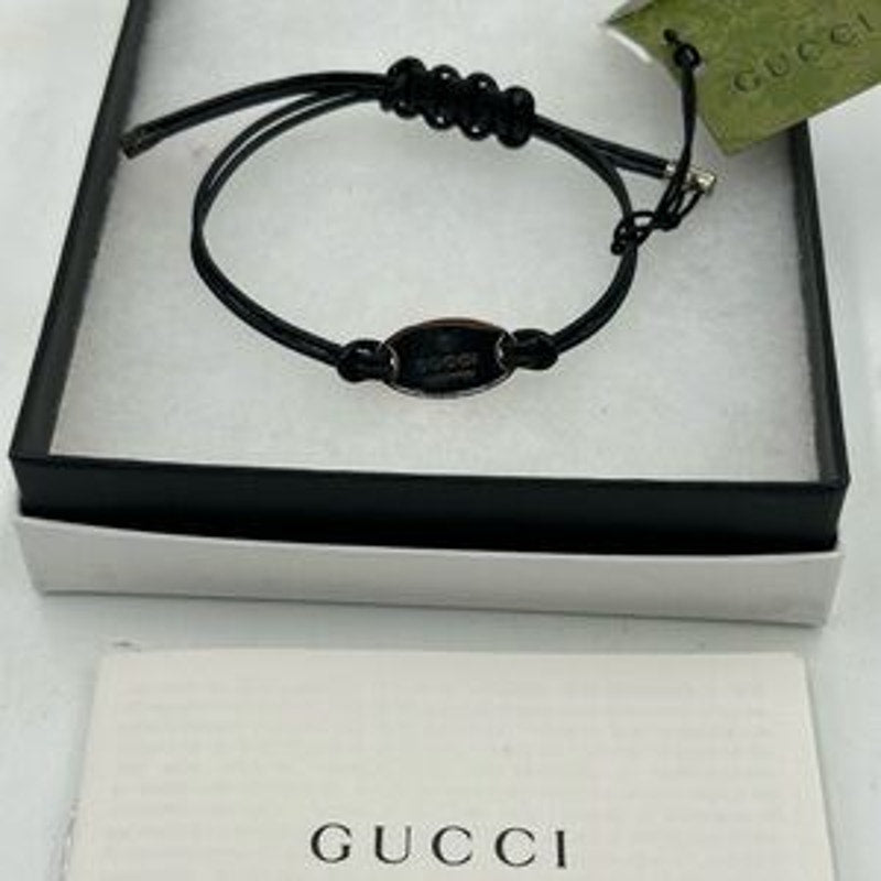Gucci, black leather cord bracelet with sterling silver logo engraved plaque