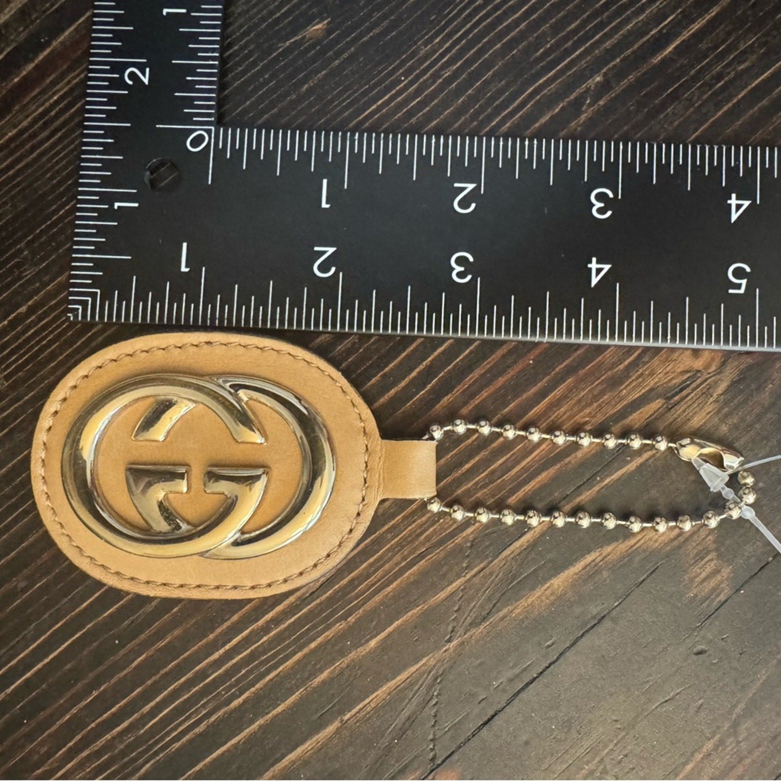 Gucci, gold logo,/tan leather, bag charm 
W/removable gold chain, add 2 any bag