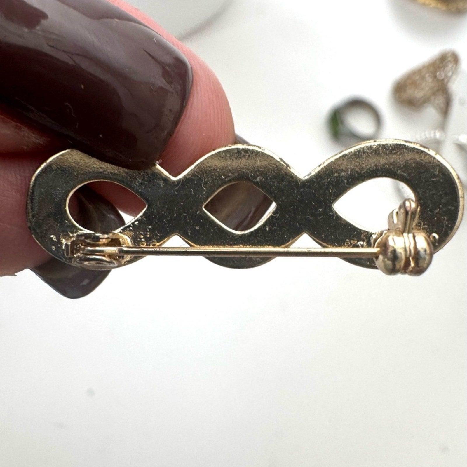 Gold Infinity pin with a closure that rotates around to keep it secure