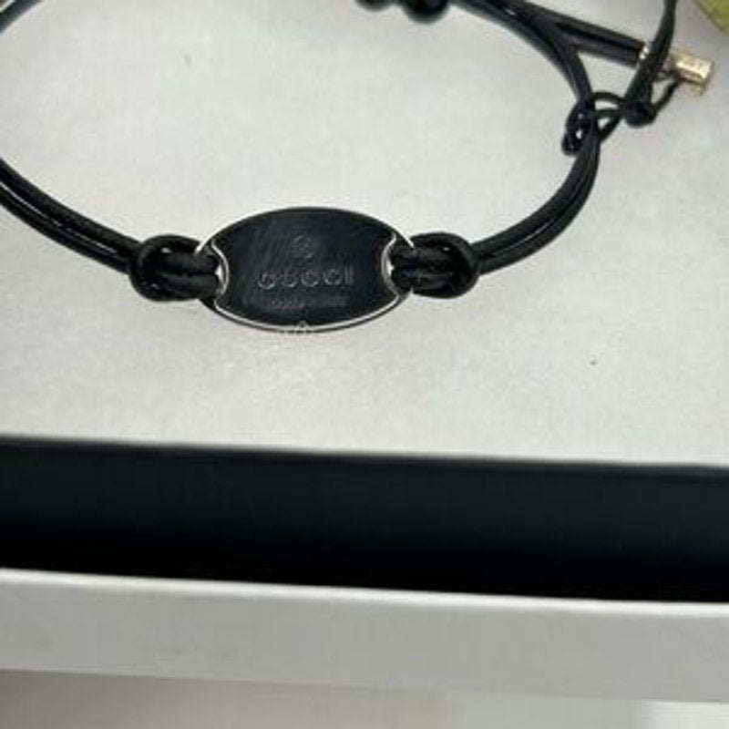 Gucci, black leather cord bracelet with sterling silver logo engraved plaque