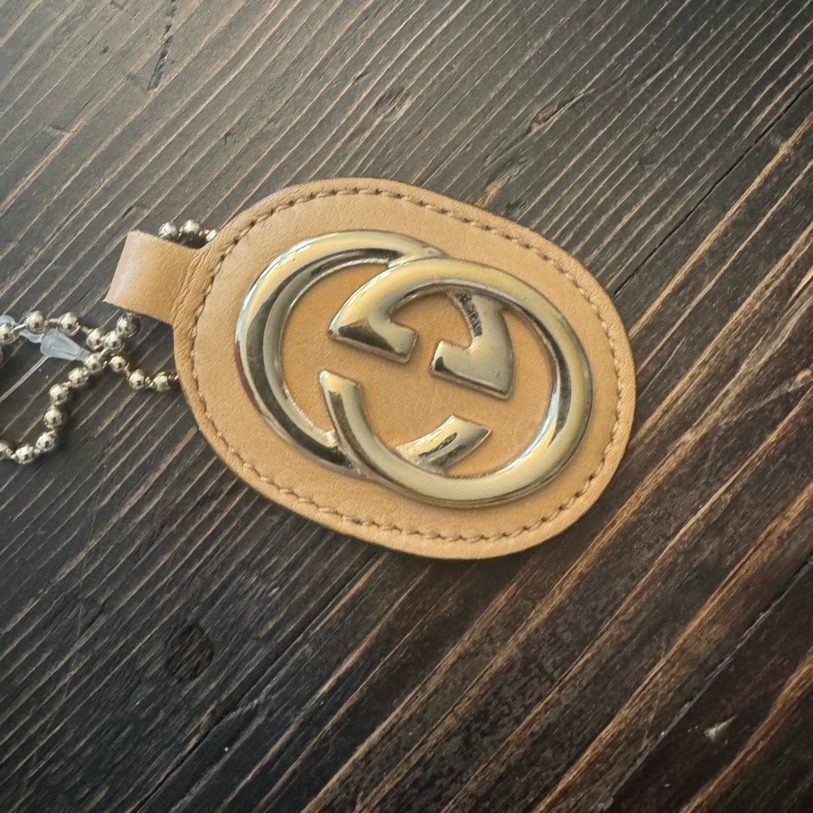 Gucci, gold logo,/tan leather, bag charm 
W/removable gold chain, add 2 any bag