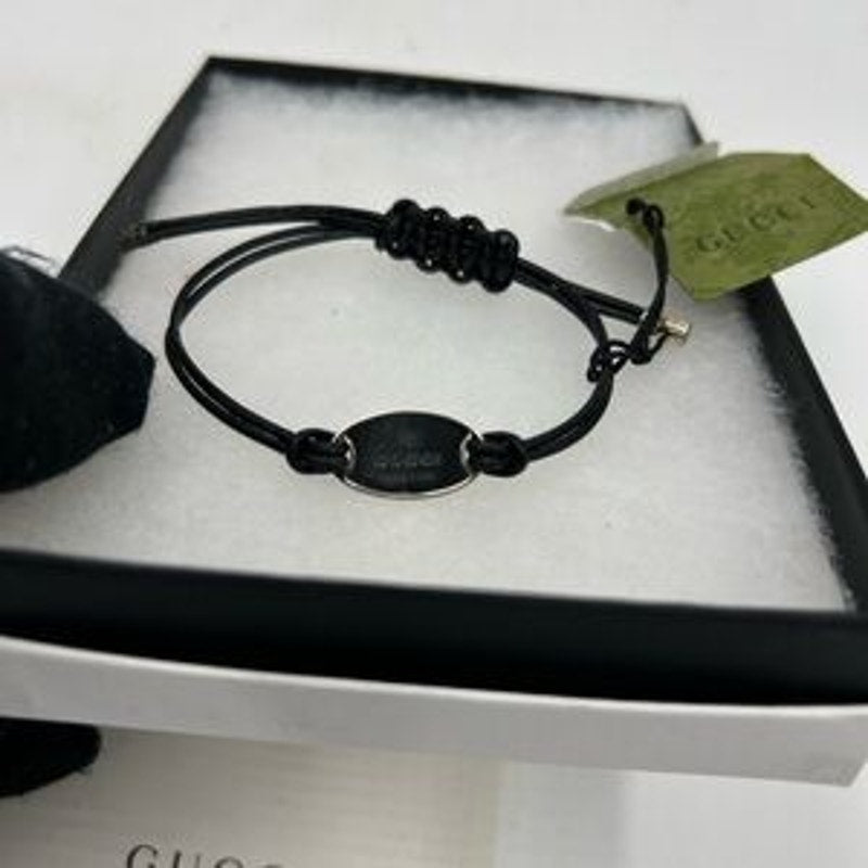 Gucci, black leather cord bracelet with sterling silver logo engraved plaque